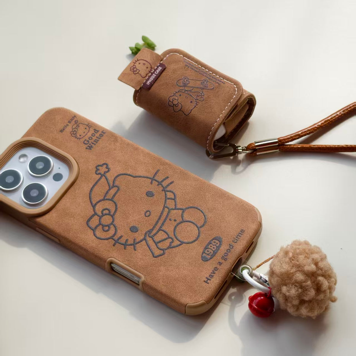 Vintage Hello Kitty Leather iPhone Case & AirPods Case Set with Pom Pom Charm | 2026 Trending Retro Kawaii Winter Accessory | Fits iPhone 12-17 Pro Max & AirPods 1/2/3/Pro